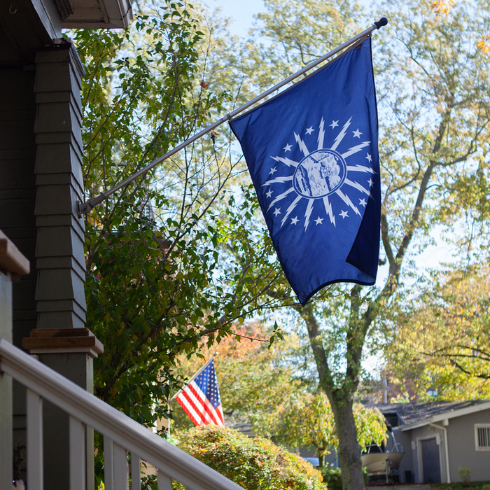 BLUE FLAG WITH A SHORE AND LIGHTHOUSE IN THE CENTER WITH LIGHTNING BOLTS AROUND THE CENTER ON A POLE OUTSIDE