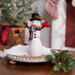 Decorative felted snowman figurine with a plaid scarf and top hat holding a cardinal