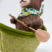 felted bear in a green boat with a paddle on a white background