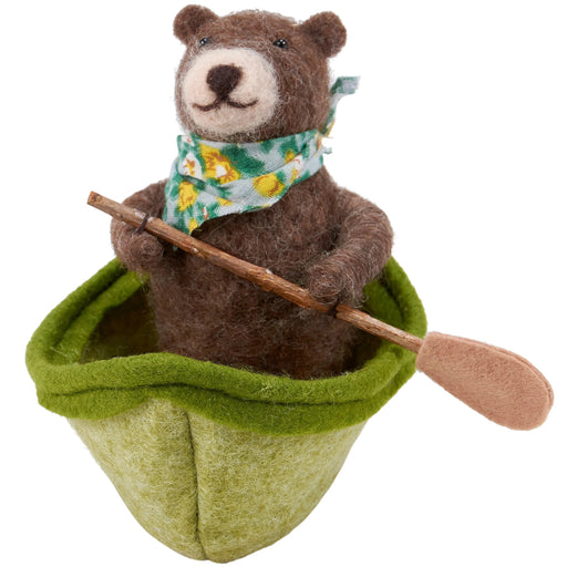 felted bear in a green boat with a paddle on a white background