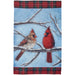 Garden flag with two cardinals on a branch against a blue sky background and snow