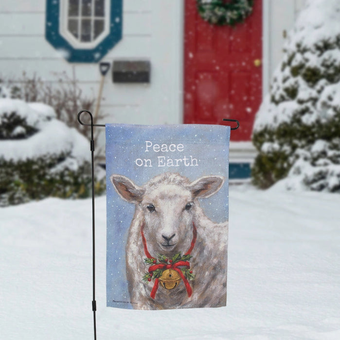 Decorative garden flag with a sheep wearing a Christmas wreath and bell, featuring the text 'Peace on Earth'.
