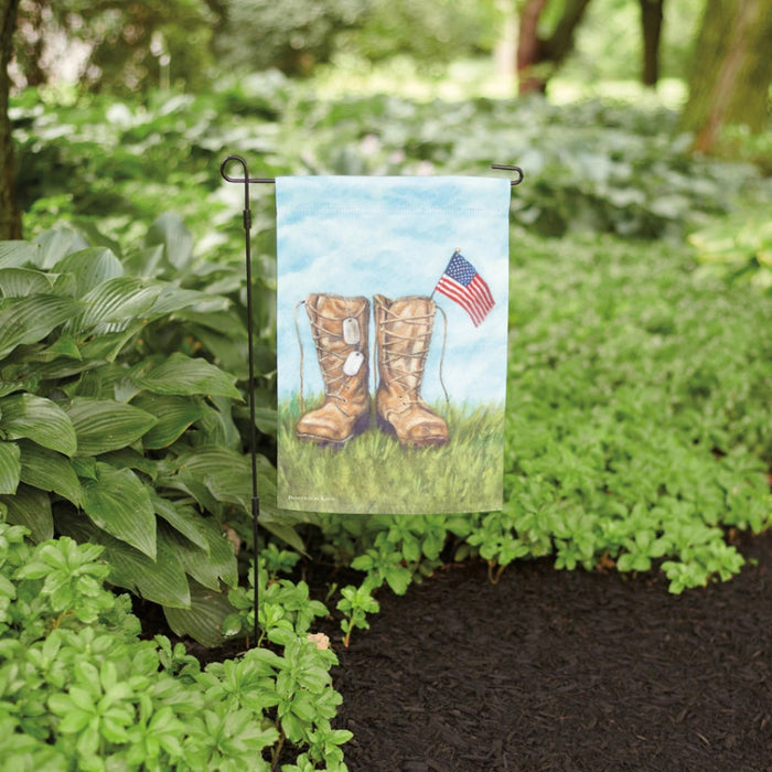 Garden flag with boots and American flag against a blue sky and grass background