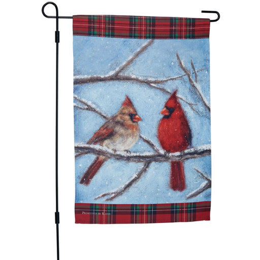 Garden flag with two cardinals on a branch against a blue sky background and snow