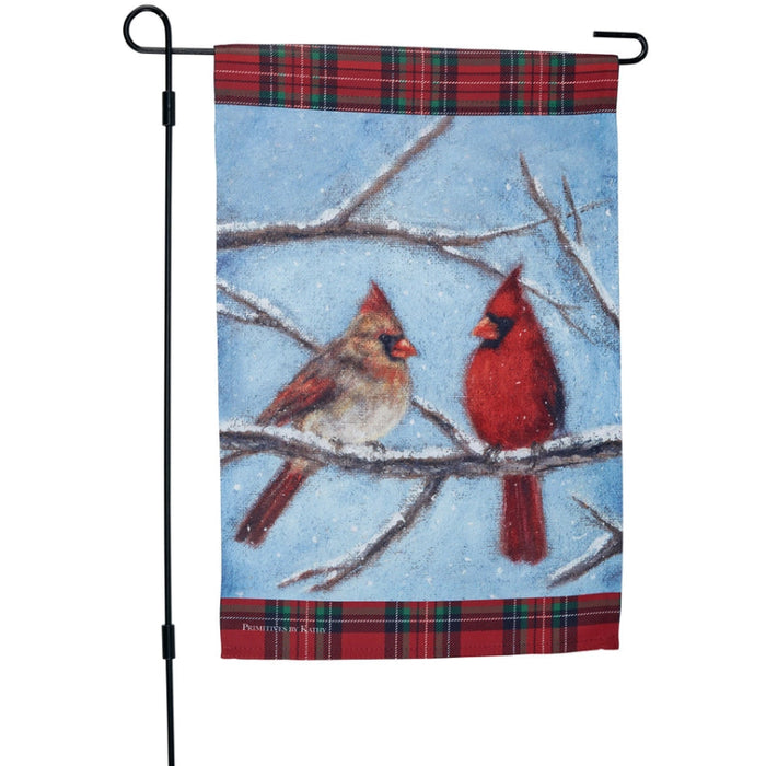 Garden flag with two cardinals on a branch against a blue sky background and snow