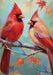 Decorative flag with two red cardinals on a branch against a colorful background with fall leaves