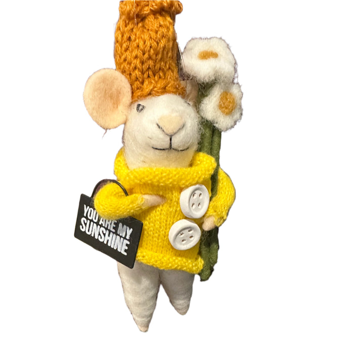 Stuffed mouse toy wearing a yellow sweater and hat, holding flowers and holding a sign