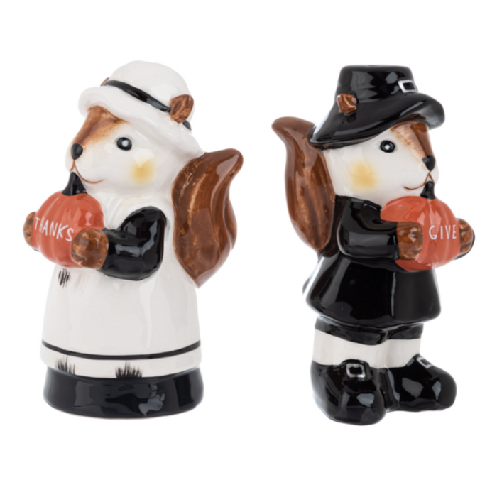 Two ceramic squirrel salt and pepper shakers, one in a pilgrim outfit and the other in a maid outfit, holding pumpkins that say "Give" "Thanks".