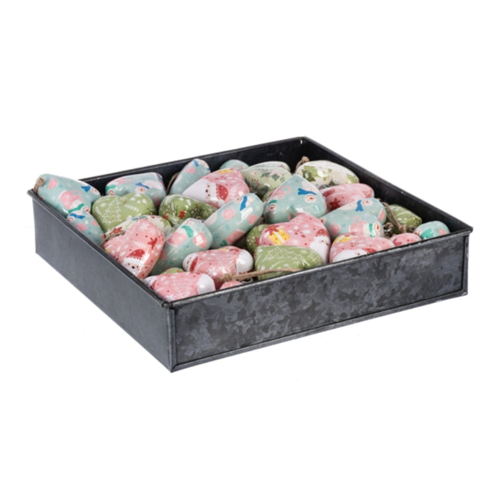 Decorative Christmas ornaments in a black tray on a white background