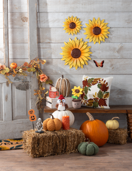 Autumn-themed decor with pumpkins, sunflowers, and decorative pillows against a wooden wall.