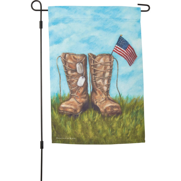Garden flag with boots and American flag against a blue sky and grass background