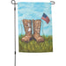 Garden flag with boots and American flag against a blue sky and grass background