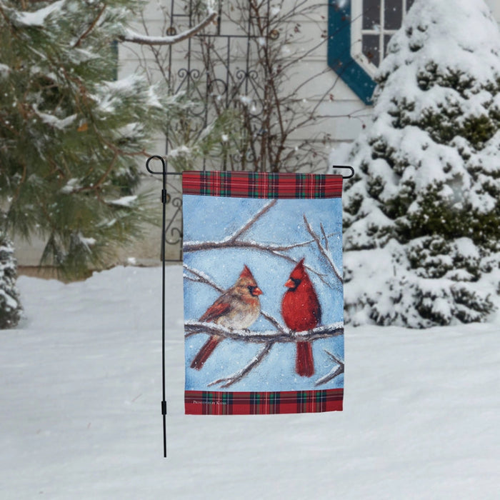 Garden flag with two cardinals on a branch against a blue sky background and snow