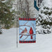 Garden flag with two cardinals on a branch against a blue sky background and snow