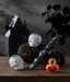 Halloween-themed decorations including skulls, a sword, and a jack-o'-lantern on a wooden surface with a dark background.