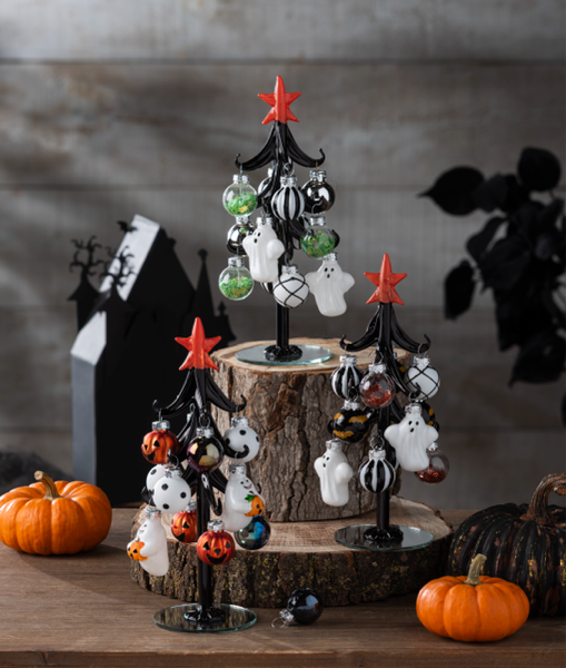 Halloween-themed decorative tree with ornaments on a wooden base, surrounded by pumpkins.