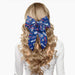 Blue hair bow with scattered Buffalo Bills logos and clip on the back side to secure to hair