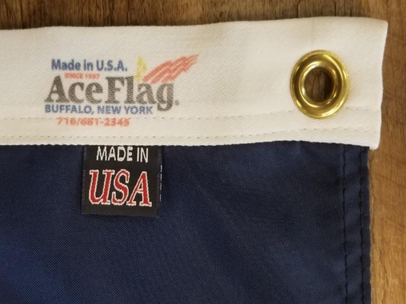 CLOSE UP OF THE GROMMET IN THE FLAG AND THE ACE FLAG LOGO ON THE HEADING